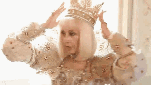 a woman in a white dress is wearing a gold crown .