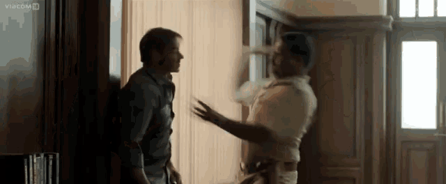 two men are standing next to each other in a room and one of them is holding another man 's arm .