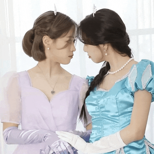 a woman in a purple dress and a woman in a blue dress looking at each other