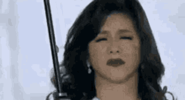 a woman is holding an umbrella in her hand and making a sad face .