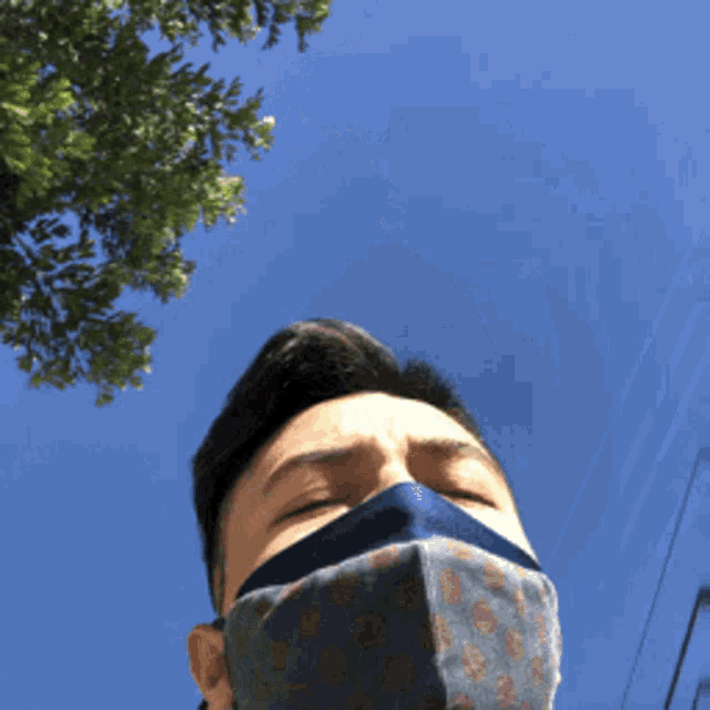 a man wearing a blue face mask looks up at the sky