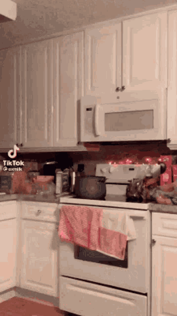 a kitchen with white cabinets and a microwave that says tiktok on it