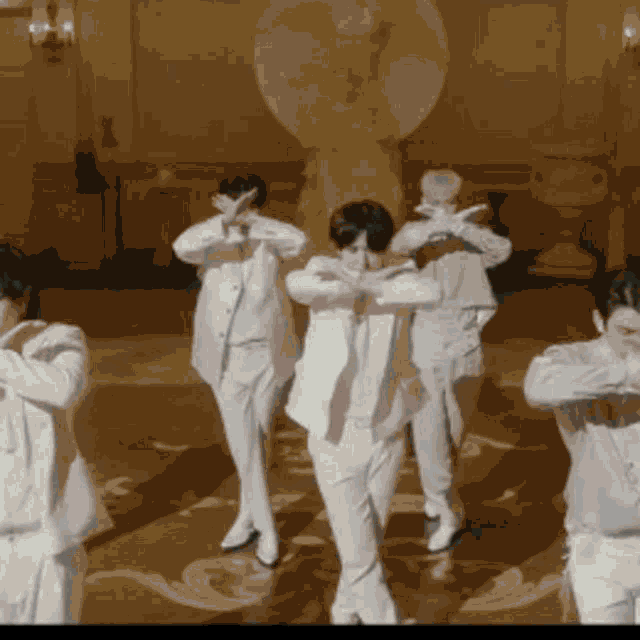 a group of men in white suits are dancing together