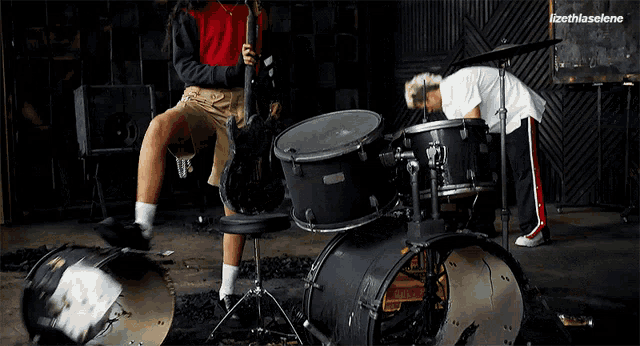 a man is playing drums in a dark room with lizeth selene written above him