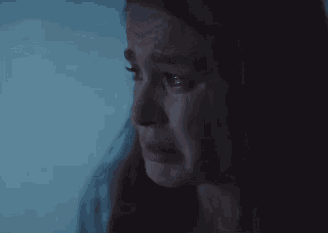 a woman is crying in a dark room in front of a window .