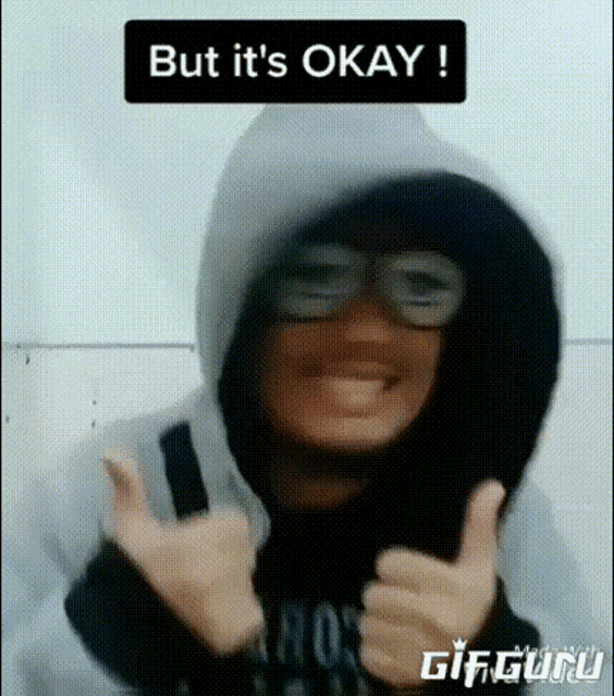 a person wearing a hoodie and glasses is giving a thumbs up