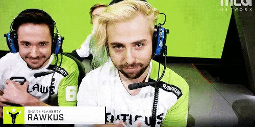 a man wearing headphones and a rawkus shirt looks at the camera