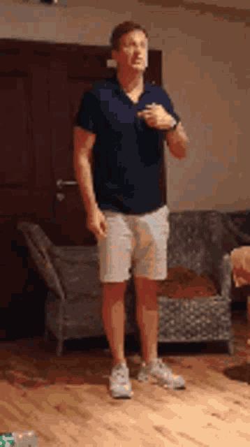 a man in a black shirt and white shorts is standing on a wooden floor .