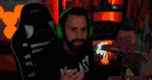 a man with a beard is wearing green headphones and sitting in a chair .