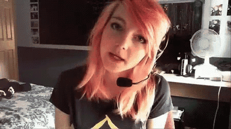 a girl with pink hair is wearing a headset and making a face .