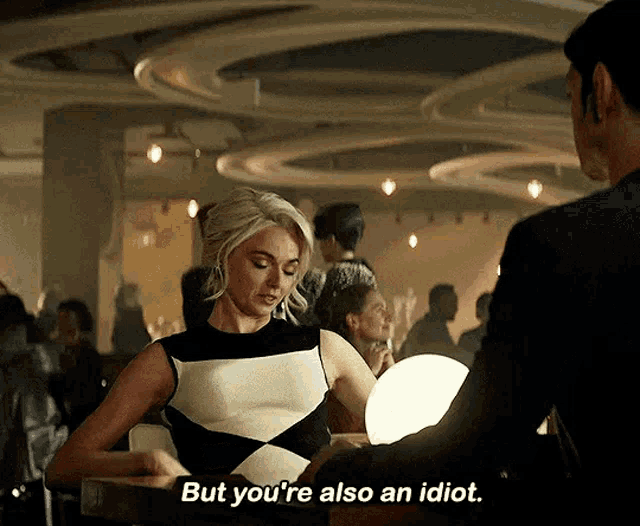 a woman in a black and white dress says " but you 're also an idiot " while standing next to a man