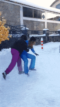 two people are playing in the snow and one of them is wearing a black jacket