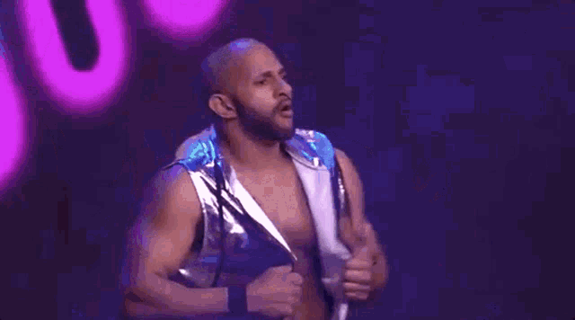 a man is taking off his shirt on a stage while another man stands behind him .
