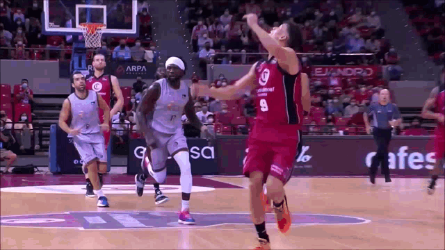 a basketball player wearing a number 9 jersey tries to block another player