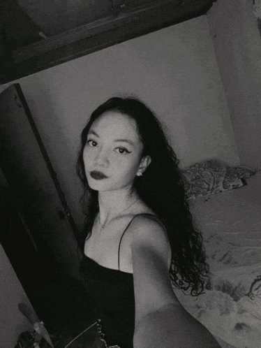 a black and white photo of a woman taking a selfie in a bedroom