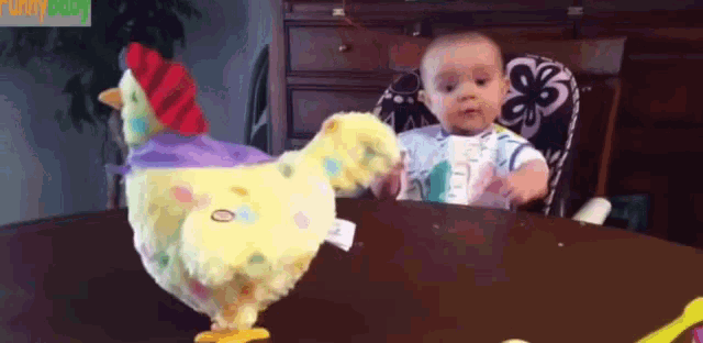 a baby is sitting at a table with a stuffed chicken