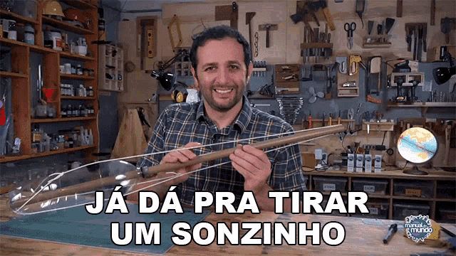 a man in a plaid shirt is holding a wooden stick with the words ja da pra tirar um sonzinho written below him