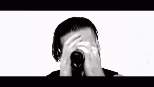 a man with a beard is singing into a microphone in a black and white video .