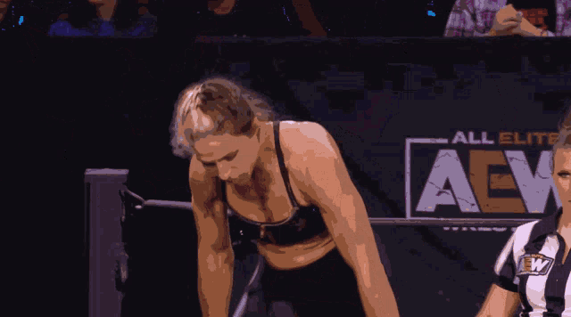 a woman in a sports bra stands next to a referee with the letter a on her uniform