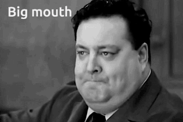 a man in a suit and tie is making a face with the words big mouth above him
