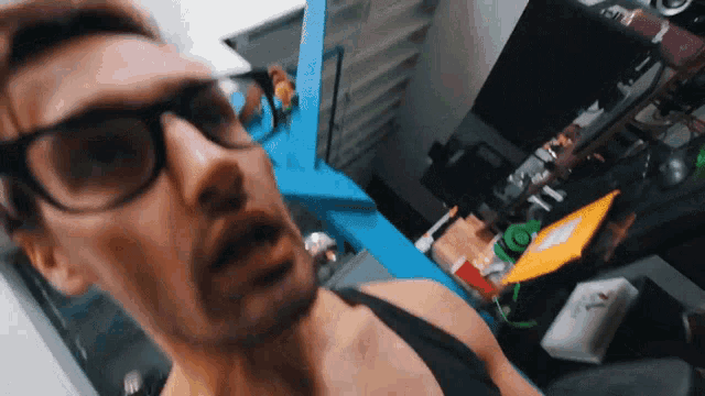 a man wearing glasses and a black tank top is looking at the camera