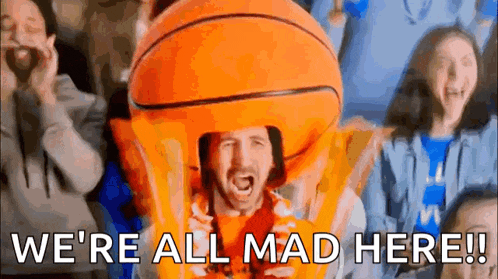 a man in an orange basketball costume is screaming in a crowd of people .