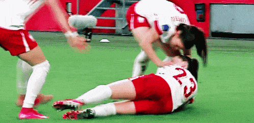 two female soccer players are fighting on the field . one of the players has the number 23 on her jersey .