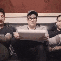 a man wearing glasses is sitting on a couch holding a piece of paper .