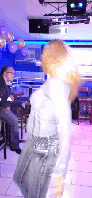 a woman dancing in a club with purple balloons on the ceiling