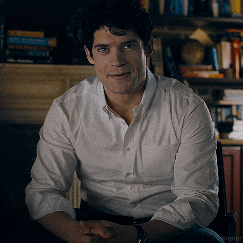 a man wearing a white shirt is sitting in a chair