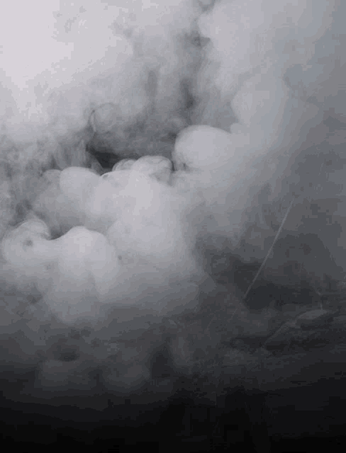 a black and white photo of smoke coming out of a hole in the ground