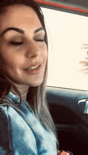 a woman is sitting in the driver 's seat of a car with her eyes closed and smiling .