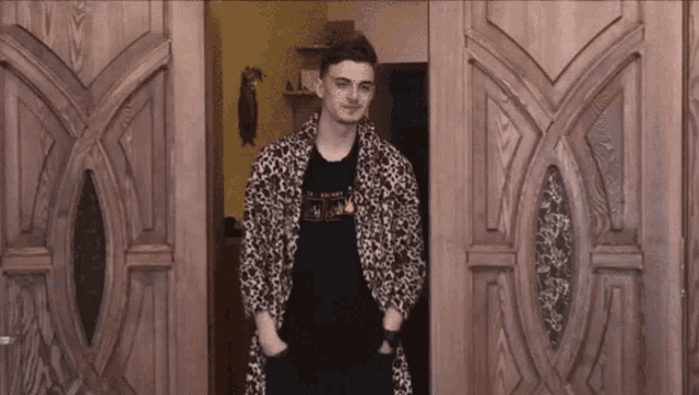 a man in a leopard print robe stands in front of a door