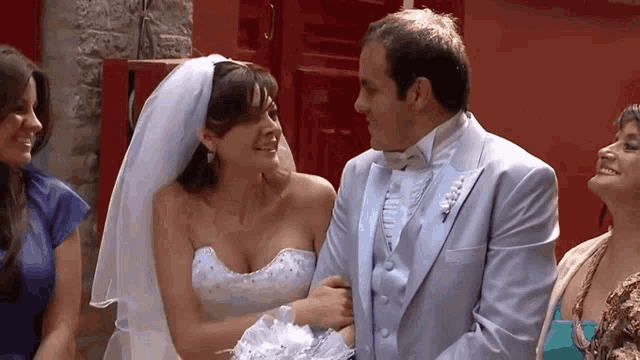 a bride and groom are standing next to each other and smiling at each other