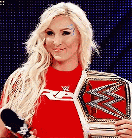 a woman in a red shirt is holding a red wrestling belt .