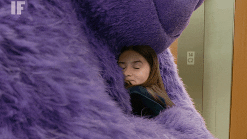 a woman is hugging a purple stuffed animal with the letters if visible