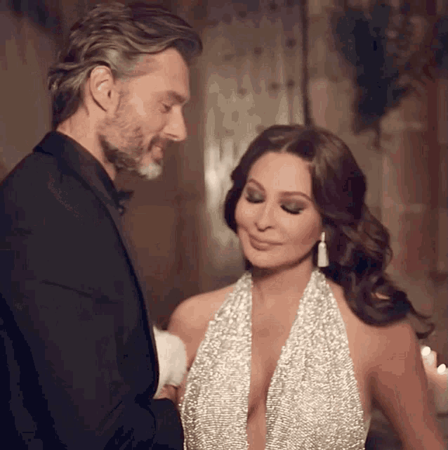 a man in a tuxedo and a woman in a dress are looking at each other