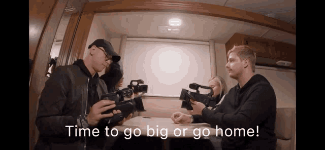 a man holding a camera with the words time to go big or go home below him