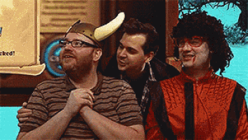 three men are sitting next to each other and one has a banana on his hat