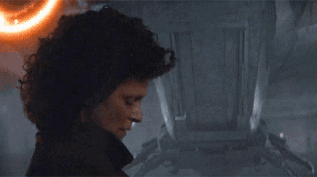 a person standing in a dark room with a robot in the foreground