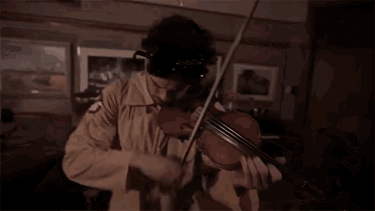a man in a military uniform is playing a violin in a dark room .