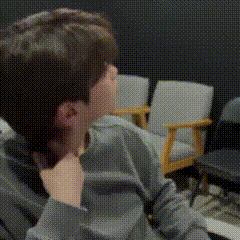 a person is sitting in a chair with their hand on their chin in a room .