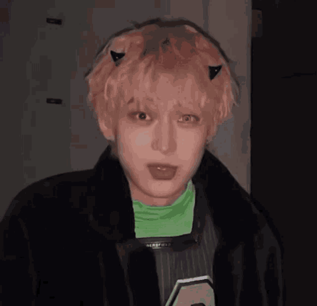 a young man with pink hair and devil horns on his head .