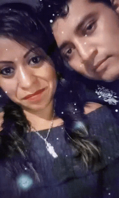 a man and a woman are posing for a picture and the woman is wearing a necklace with a butterfly on it