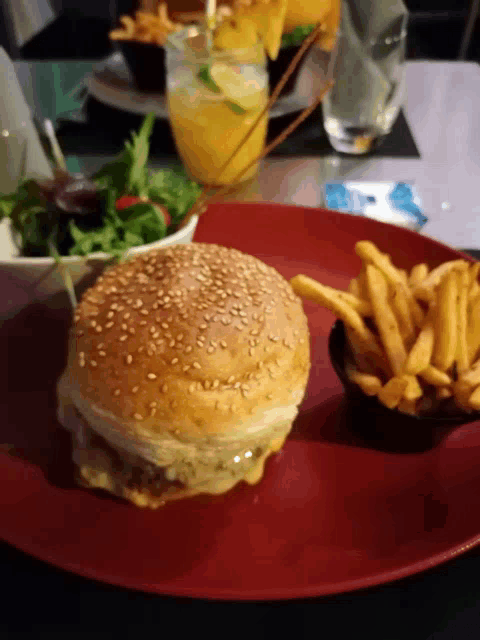 a hamburger and french fries on a red plate on a table