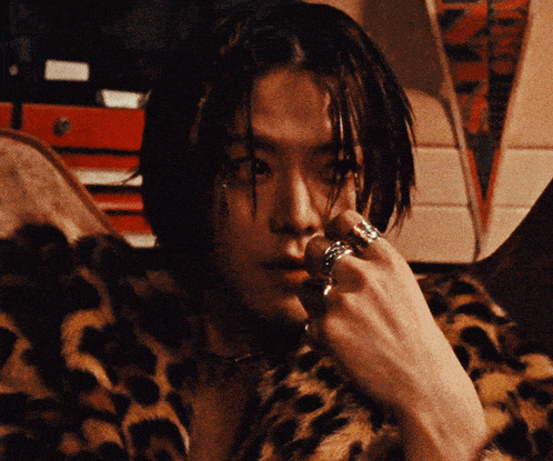 a man wearing a leopard print coat has a ring on his left hand