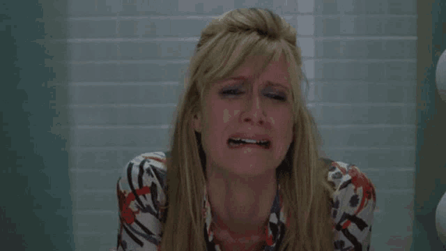 a woman is crying in a bathroom with a floral shirt on