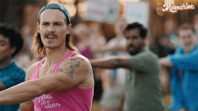 a man wearing a pink tank top that says crystal clear