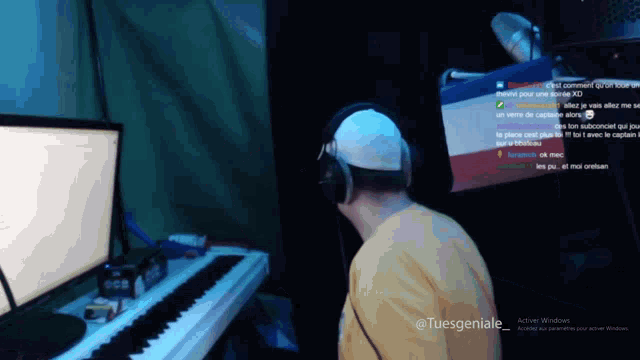 a man wearing headphones playing a piano in front of a computer monitor