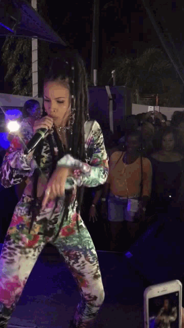 a woman with dreadlocks is singing into a microphone on stage